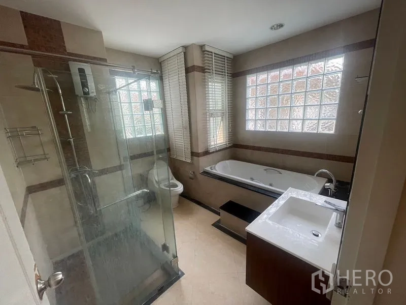 Detached House for rent or sale in Khan Na Yao, Bangkok - Contemporary bathroom with glass shower, bathtub, vanity and glass-block window.