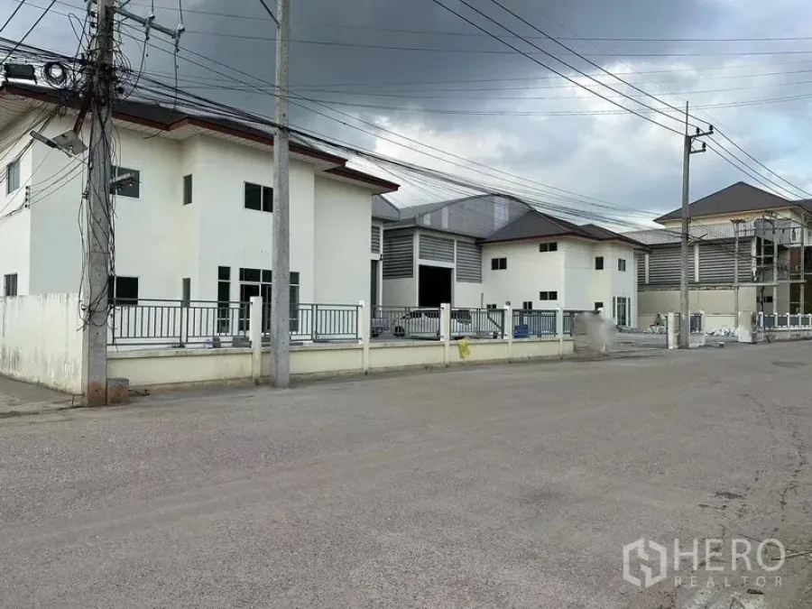 Warehouse for rent in Mueang Samut Sakhon, Samut Sakhon - Gated warehouse compound with office blocks and wide access road in Mueang Samut Sakhon under a cloudy sky.