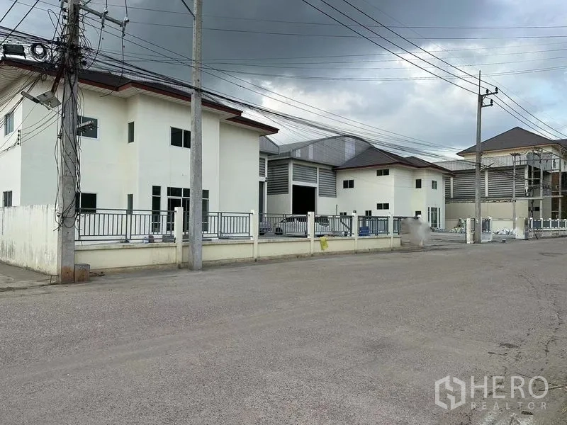 Warehouse for rent in Mueang Samut Sakhon, Samut Sakhon - Gated warehouse compound with office blocks and wide access road in Mueang Samut Sakhon under a cloudy sky.