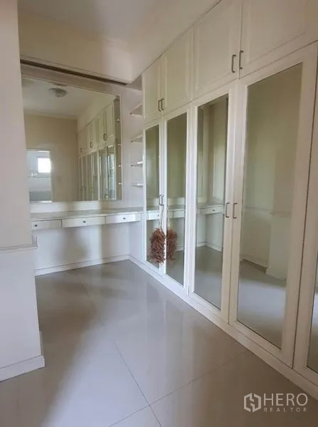Townhouse for rent in Huai Khwang, Bangkok - Walk-in closet with mirrored wardrobes and a long dressing table.