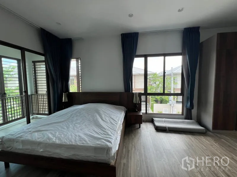 Detached House for rent in Bang Kapi, Bangkok - Large bedroom with dual balconies, dark drapes and expansive windows.