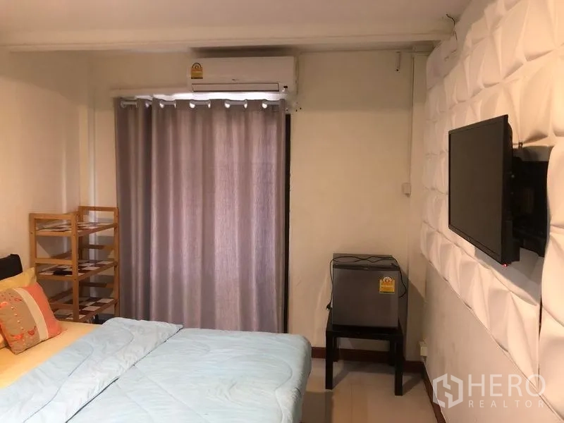 Retail Space for rent in Khlong Toei, Bangkok - Bedroom with double bed, wall-mounted TV, air conditioner and blackout curtains.