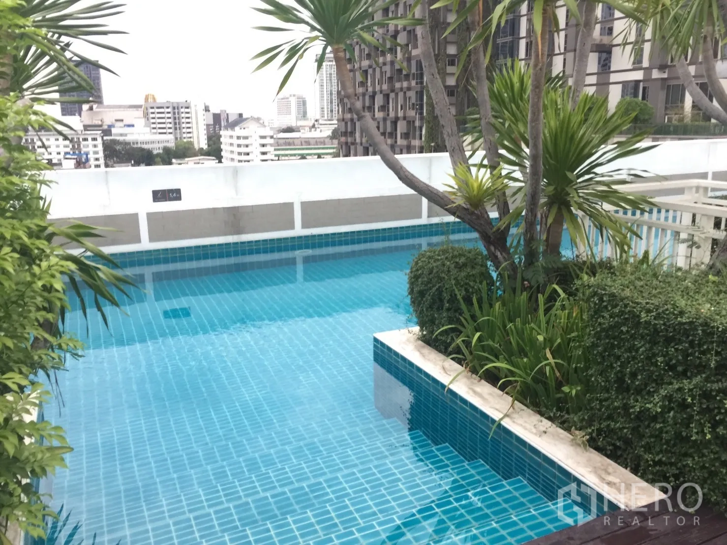 Condominium for rent in Khlong Toei, Bangkok - Rooftop swimming pool with tropical plants and city skyline views.