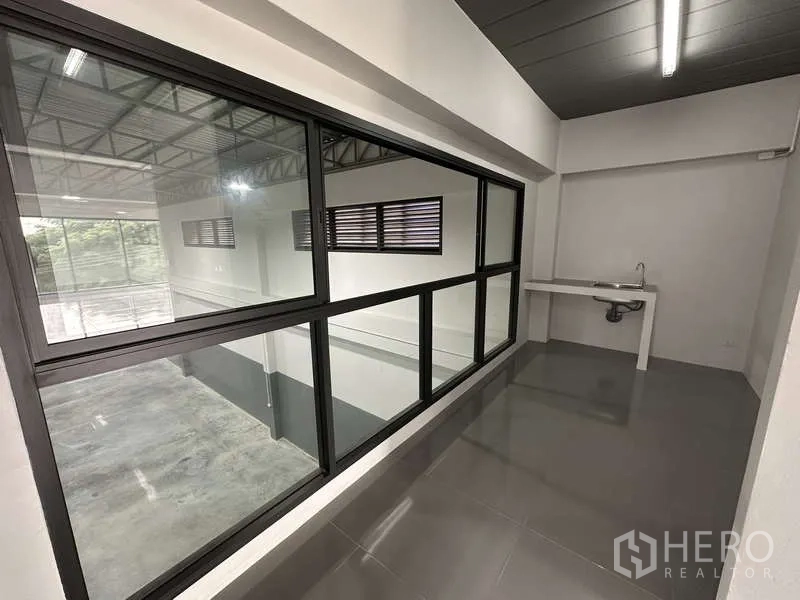 Factory for rent or sale in Bang Bua Thong, Nonthaburi - Office corridor with internal viewing window to the warehouse and a sink.