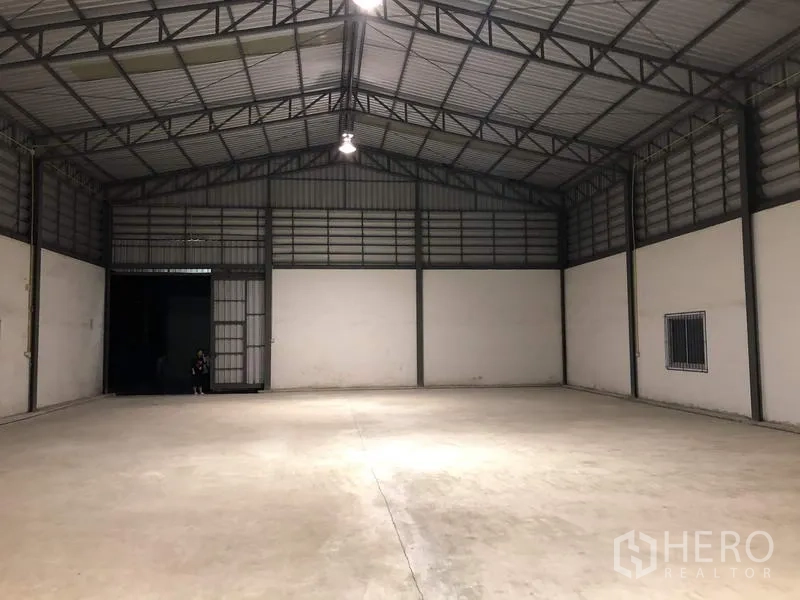 货栈 出租在Lam Luk Ka, Pathum Thani - 面向装卸门的通透库内视角，吊灯与上部通风墙体清晰可见。