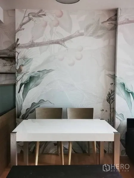 Condominium for sale in Khlong Toei, Bangkok - Dining nook with white table and two chairs against botanical wall art.