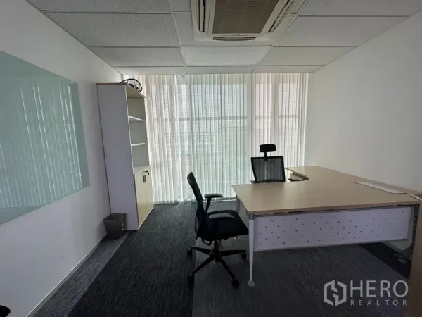Office Space for rent - Private office with large desk, ergonomic chair, carpet tiles and floor-to-ceiling windows with vertical blinds.