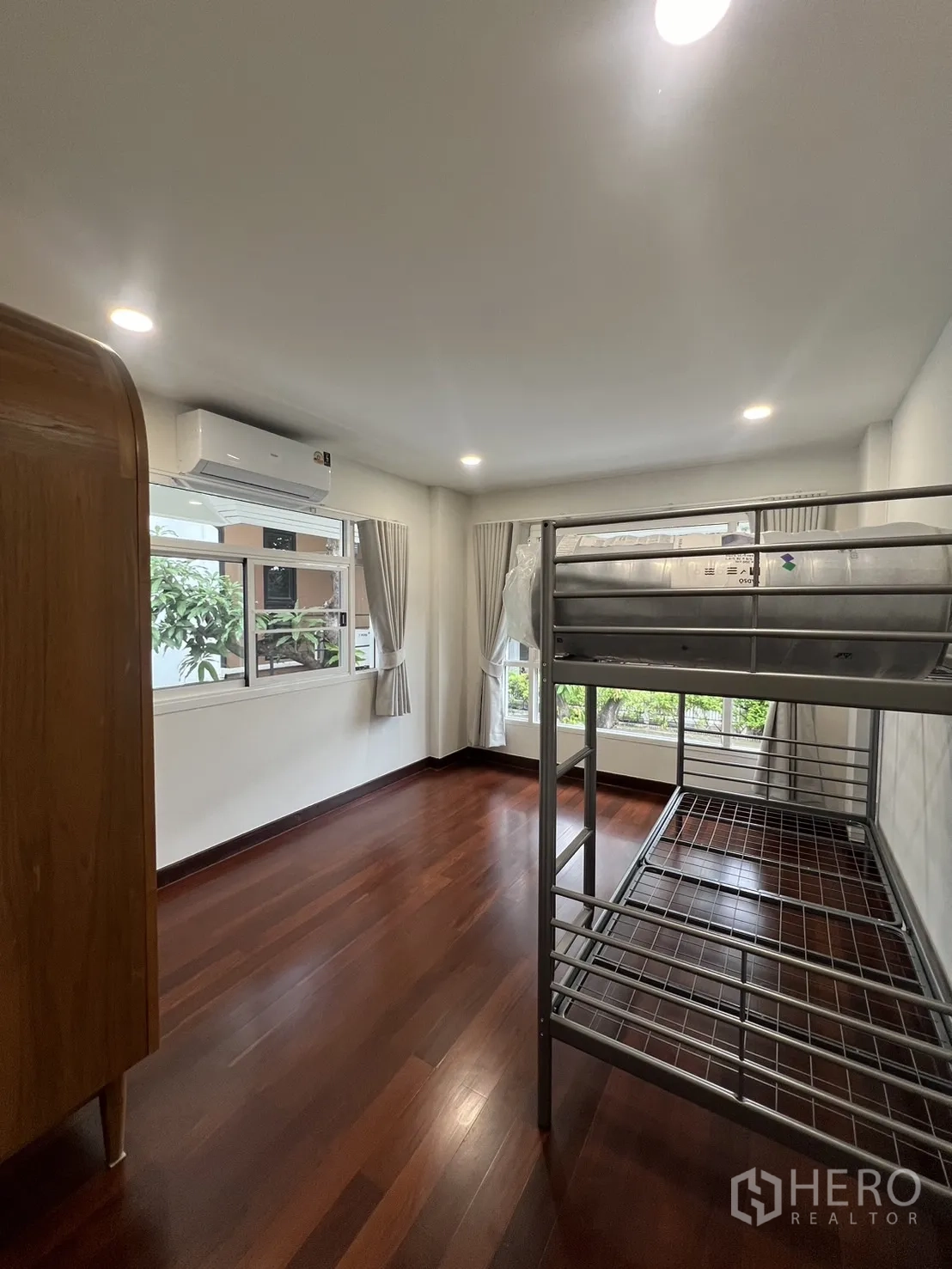 Detached House for rent in Saphan Sung, Bangkok - Kids’ bedroom with wooden floor and metal bunk bed by corner windows.