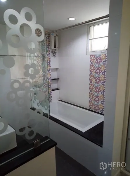 Condominium for rent in Watthana, Bangkok - Modern bathroom with bathtub, frosted glass partition, and window for ventilation.