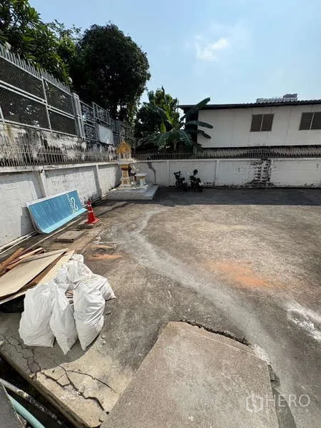 Standalone for rent in Khlong Toei, Bangkok - Concrete yard with boundary wall and small spirit house.