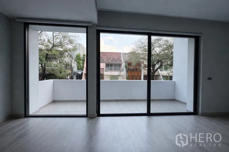 บ้านแฝด for rent in Watthana, Bangkok - พื้นที่รับแขกมีประตูกระจกสูงเต็มผนังเปิดออกสู่ระเบียงกว้าง