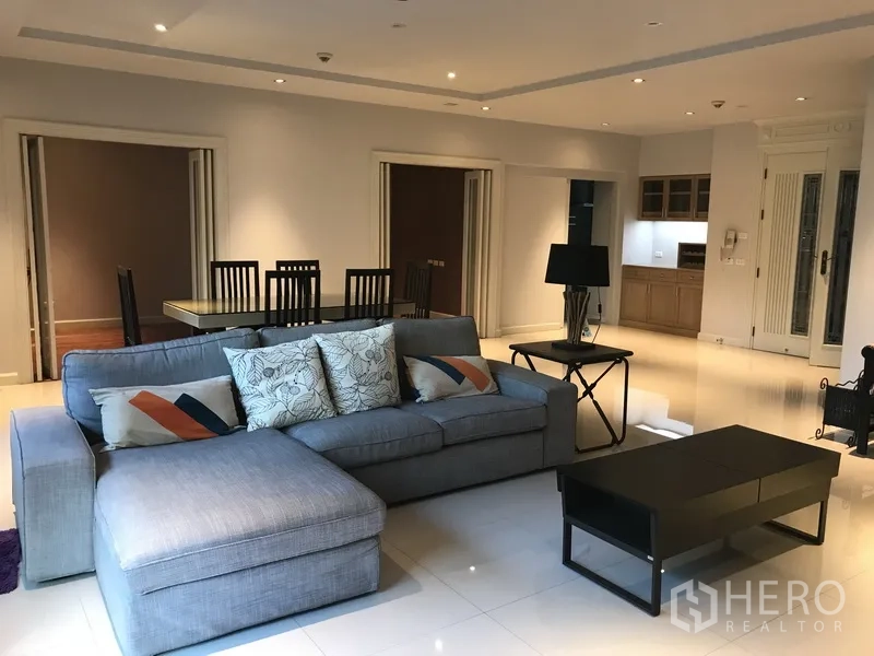 房间 出租在Pathum Wan, Bangkok - 宽敞客厅，L型沙发、餐桌与紧凑厨房相连