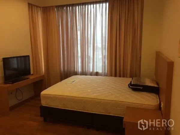Condominium for rent in Watthana, Bangkok - Cozy bedroom with large window and sheer curtains, TV on wooden desk, and a double bed.