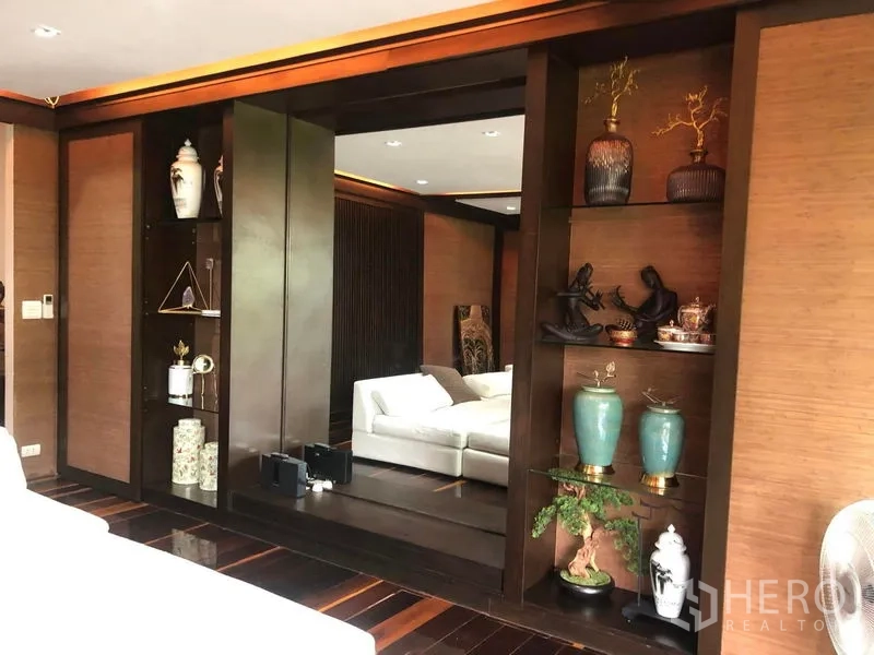 Townhouse for rent in Yan Nawa, Bangkok - Elegant lounge or bedroom with built-in shelving, large mirror, and warm wood finishes.