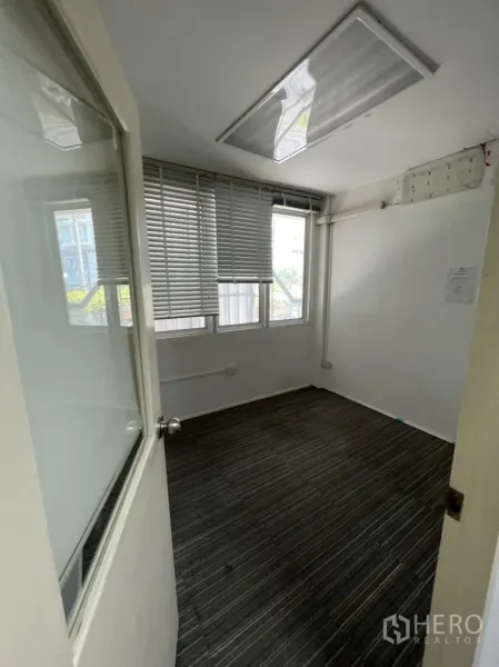 Shophouse for rent or sale in Watthana, Bangkok - Compact carpeted office with windows and horizontal blinds.