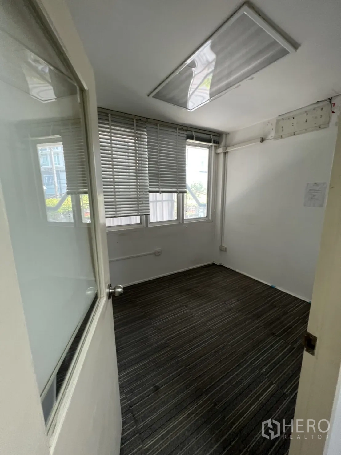 Shophouse for rent or sale in Watthana, Bangkok - Compact carpeted office with windows and horizontal blinds.