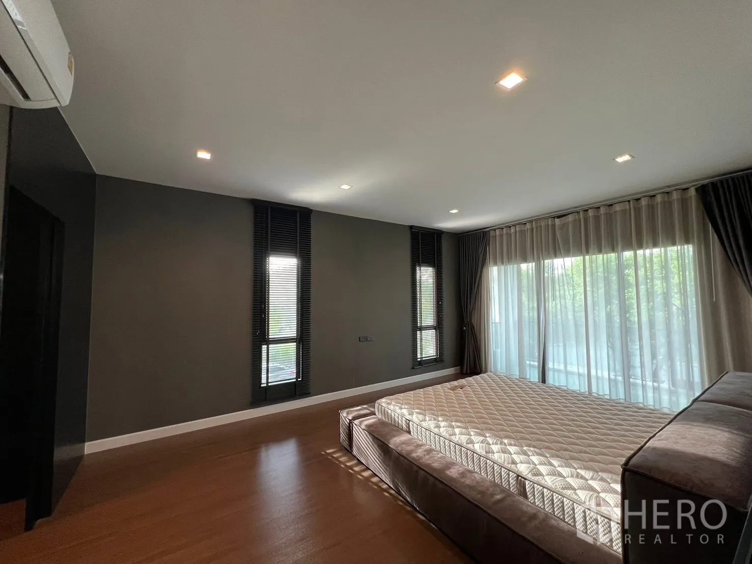 บ้าน ให้เช่าในBang Phli, Samut Prakan - ห้องนอนสว่างพร้อมม่านโปร่งหน้ากว้าง หน้าต่างแนวตั้ง และไฟดาวน์ไลท์เหนือพื้นไม้