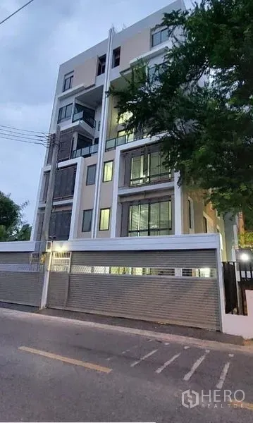 带办公室的家 出租在Huai Khwang, Bangkok - 街景视角的当代外立面，窗户点亮并设有周边围墙。