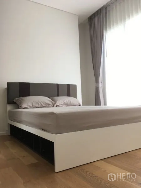 Condominium for rent or sale in Chatuchak, Bangkok - Bright bedroom featuring a white platform bed, grey headboard and sheer curtains.