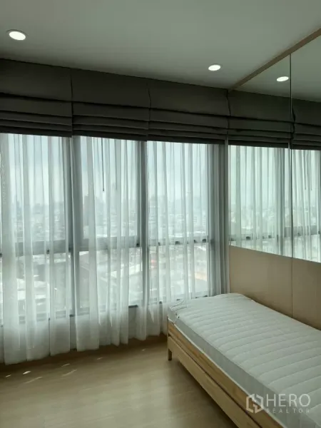 公寓 出租在Khlong Toei, Bangkok - 落地窗配纱帘的卧室一角，自然采光与单人床。
