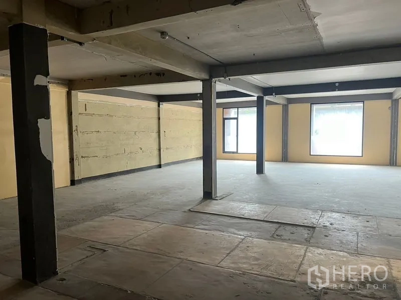Retail Space for rent in Watthana, Bangkok - Open-plan retail floor with concrete flooring, exposed beams, and large windows in Watthana, Bangkok.