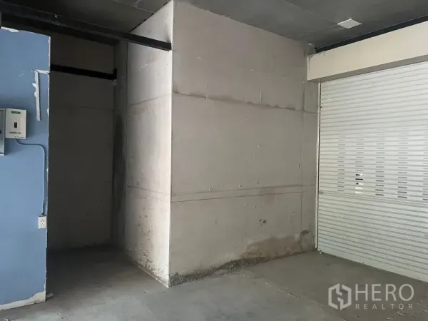 Retail Space for rent in Khlong Toei, Bangkok - Interior corner of the shop showing a partitioned back area, utility panel and a closed shutter door.