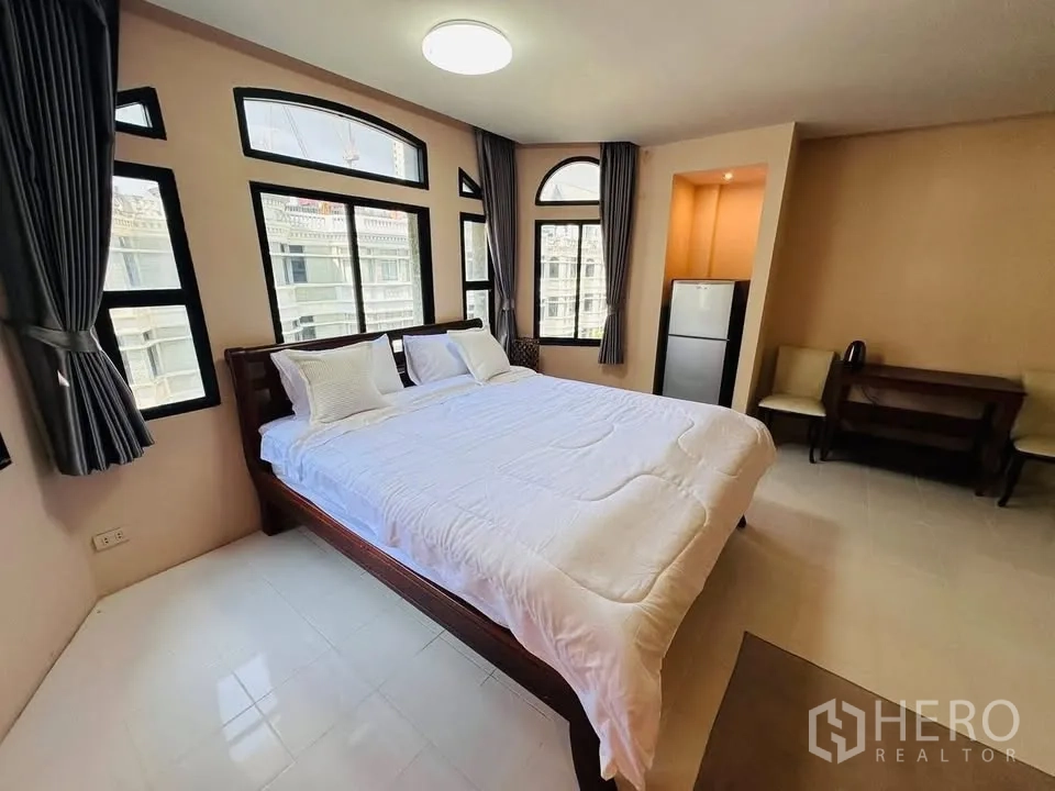 ทาวน์เฮาส์ for rent - ห้องนอนสว่างพร้อมเตียงขนาดใหญ่ หน้าต่างโค้งหลายบาน ผ้าม่าน โต๊ะทำงาน และตู้เย็น