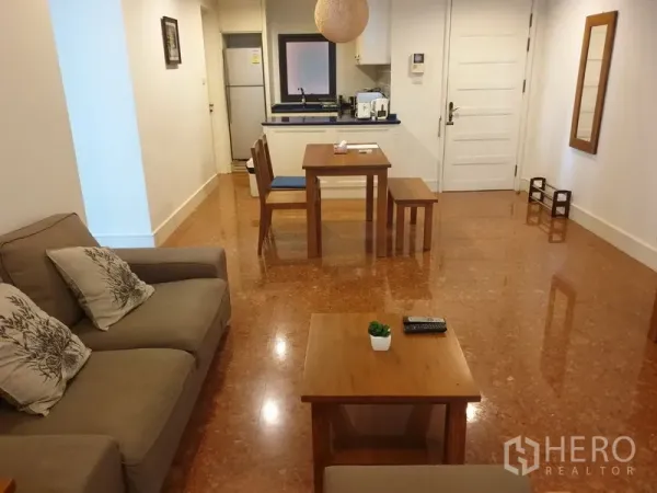 公寓 出租或出售在Khlong Toei, Bangkok - 开放式客餐厅，配沙发、木质茶几与紧凑厨房的曼谷公寓室内。