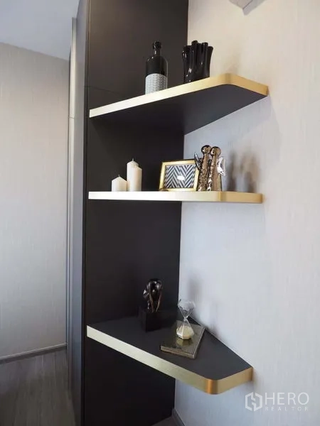 Condominium for rent in Khlong San, Bangkok - Corner floating shelves with gold trim displaying decorative accessories and candles.