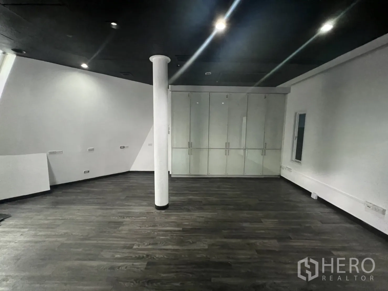 Retail Space for rent in Sathon, Bangkok - Dark-ceiling showroom with white column and a wall of glass-front cabinets.