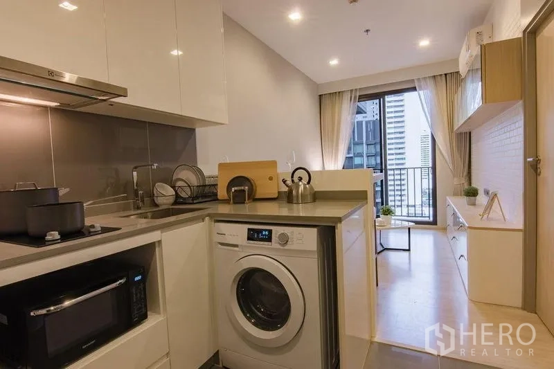 Condominium for sale in Watthana, Bangkok - Fully fitted kitchenette with hob, sink, washer and microwave leading to the living room and balcony.