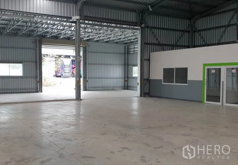 货栈 出租在Pak Kret, Nonthaburi - 朝向宽装卸门的内部视角，自然采光，旁有办公室单元。