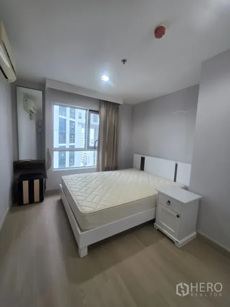 Condominium for rent in Huai Khwang, Bangkok - Bedroom with double bed, bedside table, and window with city view.