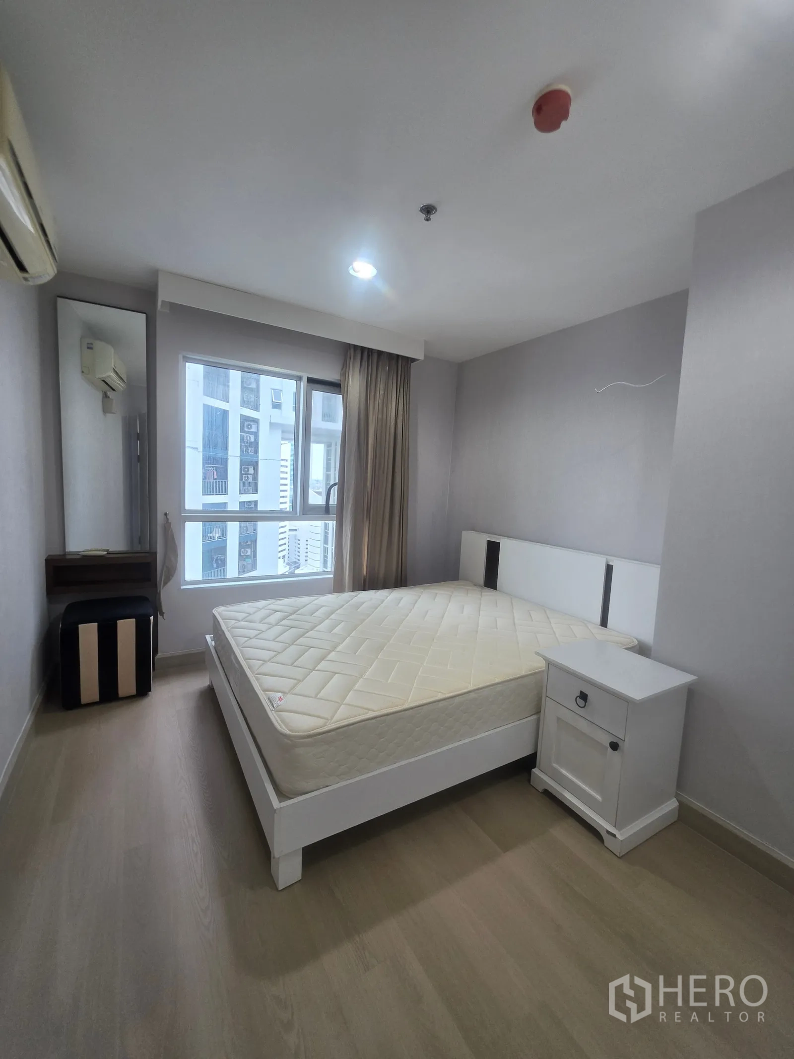 Condominium for rent in Huai Khwang, Bangkok - Bedroom with double bed, bedside table, and window with city view.