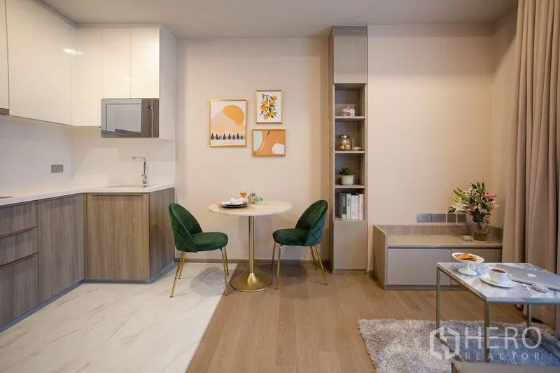 Condominium for rent in Watthana, Bangkok - Open-plan kitchen with wood cabinetry, round dining table and green velvet chairs.
