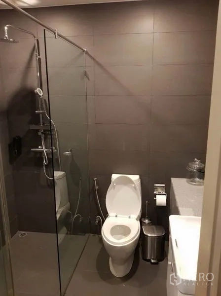 Condominium for rent in Pathum Wan, Bangkok - Modern bathroom with glass-enclosed shower, handheld spray and vanity.