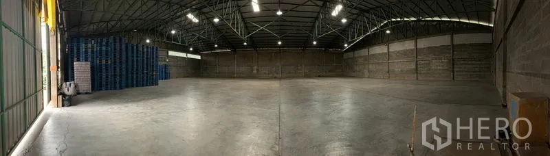 Warehouse for rent in Mueang Pathum Thani, Pathum Thani - Panoramic view of empty warehouse floor showing column-free layout, overhead lighting and side loading access.