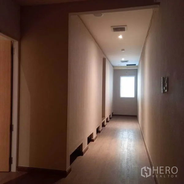 Shophouse for rent in Watthana, Bangkok - Long corridor with wood flooring and a window at the end