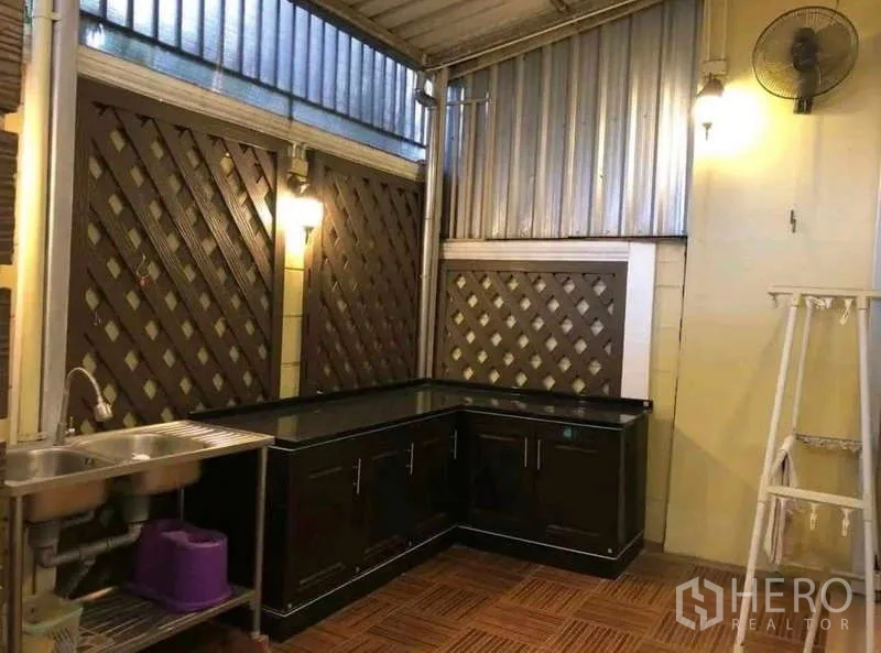 Townhouse for rent in Phra Khanong, Bangkok - Separate covered Thai kitchen with sink, U-shaped counters and ventilation fan.