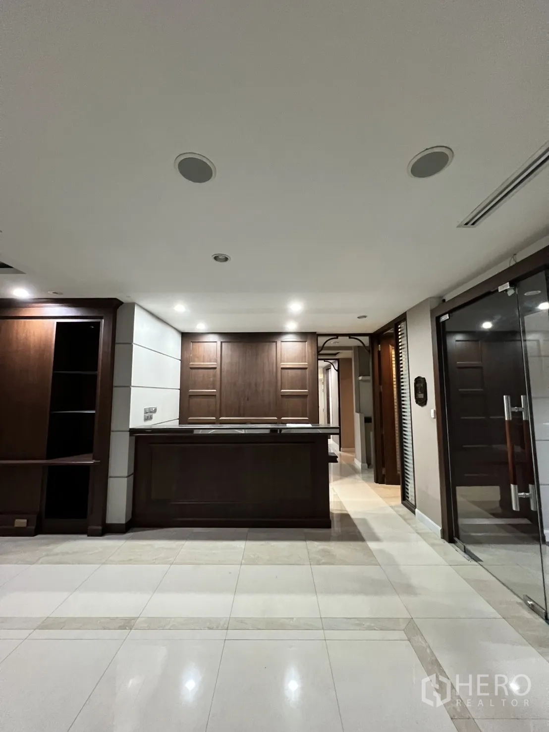 Office Space for rent in Watthana, Bangkok - Front view of a dark wood reception desk under ceiling lights.