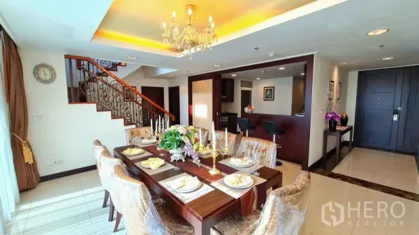 Apartment for rent in Watthana, Bangkok - Elegant dining area with chandelier beside an internal staircase in a duplex apartment.