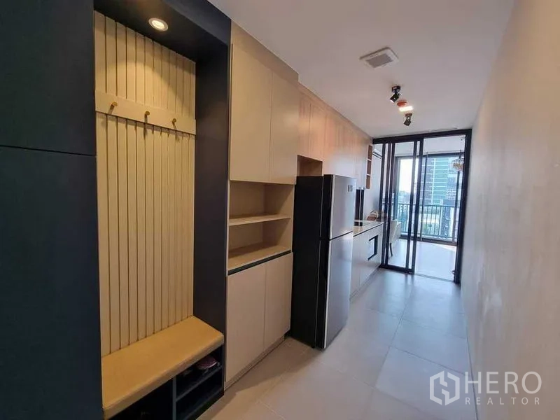 Condominium for rent in Ratchathewi, Bangkok - Galley kitchen with built-in cabinets, refrigerator and balcony city view.