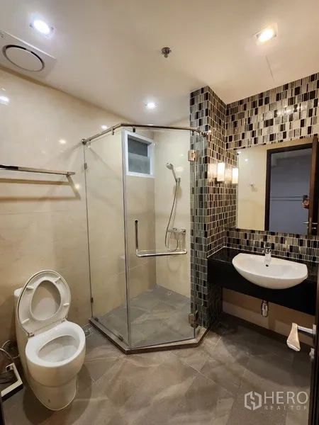 Condominium for rent in Khlong Toei, Bangkok - Bathroom with glass shower enclosure and mosaic feature wall.