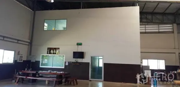 Factory for sale in Bang Phli, Samut Prakan - Interior showing a two‑storey office block with windows and a door inside the factory hall.