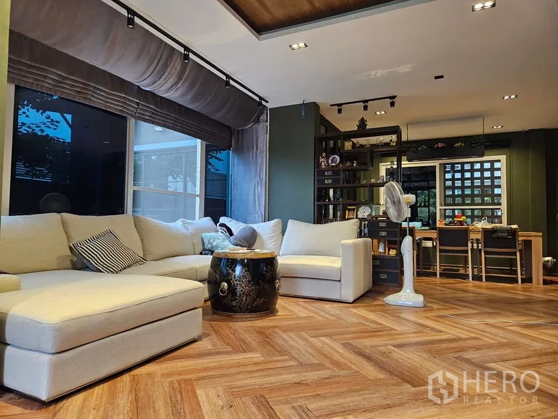 独立式住宅 出售在Thawi Watthana, Bangkok - 开放式起居区，转角沙发、书架与木地板。