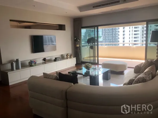 Condominium for rent in Bangkok - Bright living area with TV wall and sliding doors to a large city-view balcony.