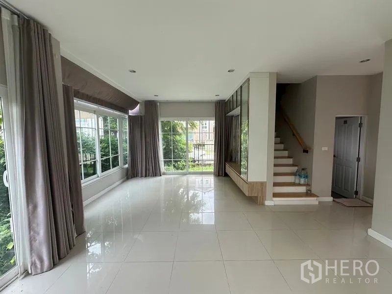 Detached House for sale in Bang Khen, Bangkok - Living room from opposite angle showing staircase and wraparound windows.