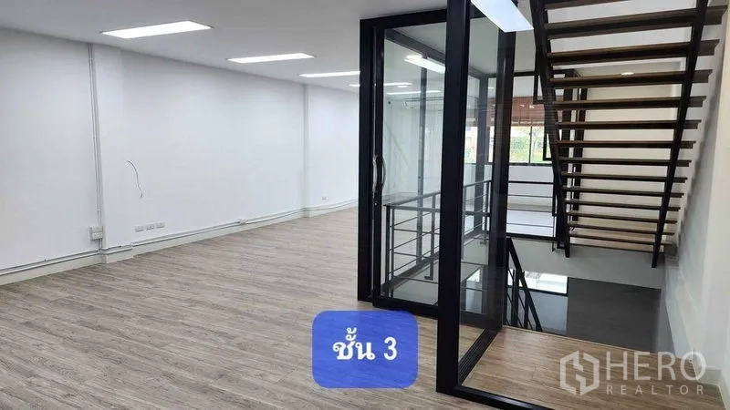 Townhouse for rent in Bueng Kum, Bangkok - Open-plan third floor with glass-enclosed staircase and bright ceiling lights.
