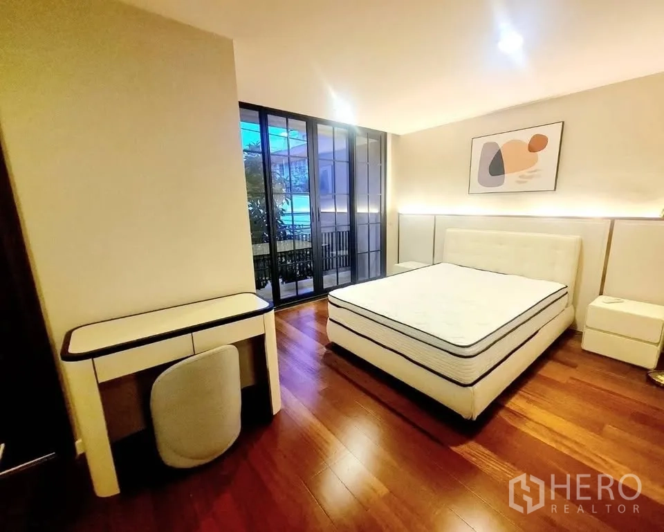 ทาวน์เฮาส์ for rent or sale in Watthana, Bangkok - ห้องนอนพร้อมโต๊ะทำงานและประตูกระจกเลื่อนออกสู่ระเบียง