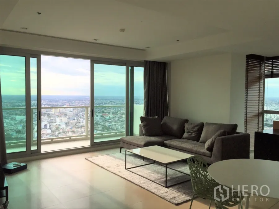 Condominium for rent or sale in Khlong San, Bangkok - Bright living room with floor-to-ceiling windows and panoramic Chao Phraya River and city views.